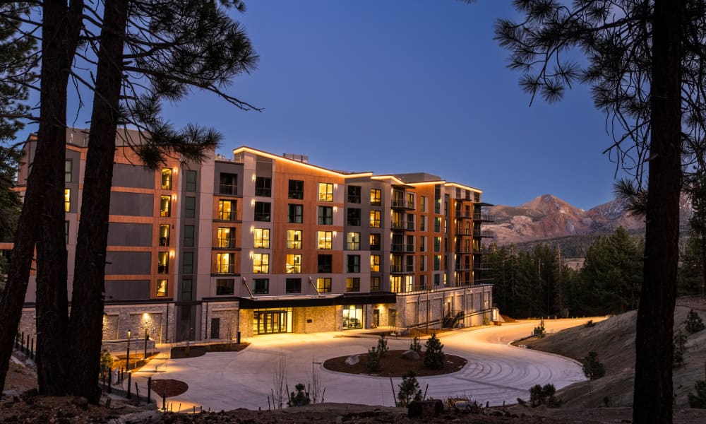 Illuminated exterior of Limelight Residences Mammoth at dusk with a circular arrival driveway and mountain backdrop.