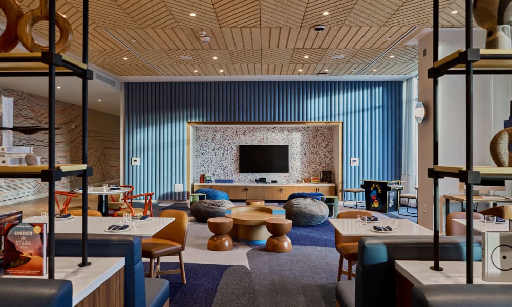Children's lounge featuring colorful seating, games, dining tables, and a large television.