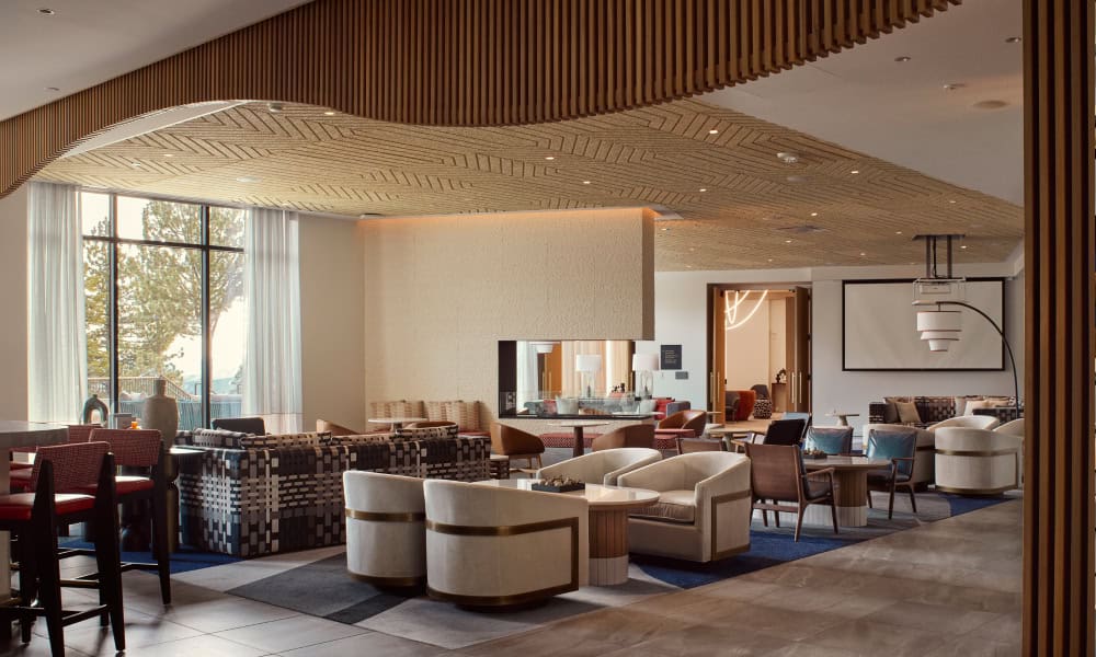 Spacious luxury lounge with modern seating, floor-to-ceiling windows, and a central fireplace.