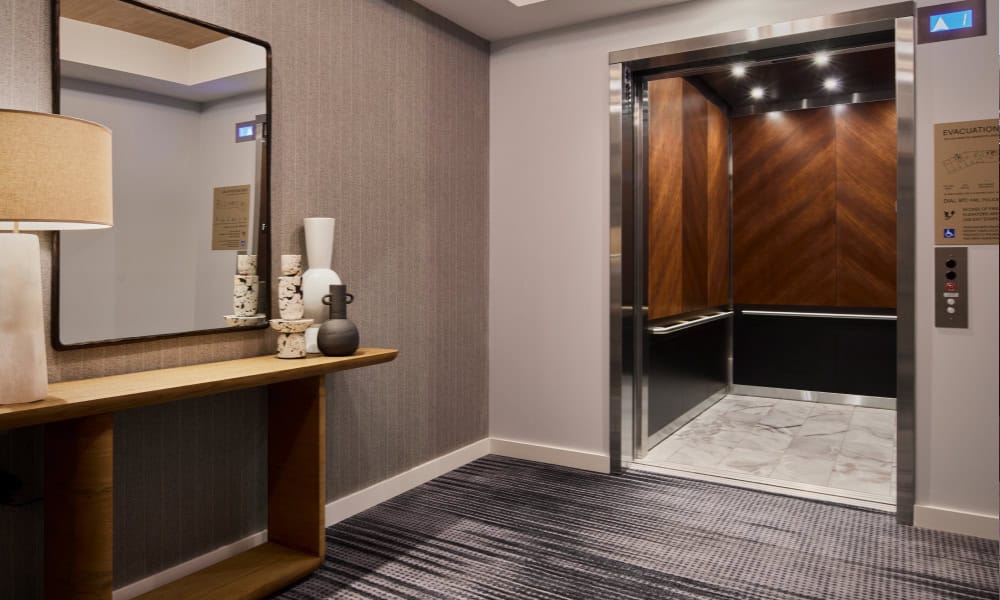 Private elevator lobby with wood-paneled elevator interior, decorative console table, and modern finishes.