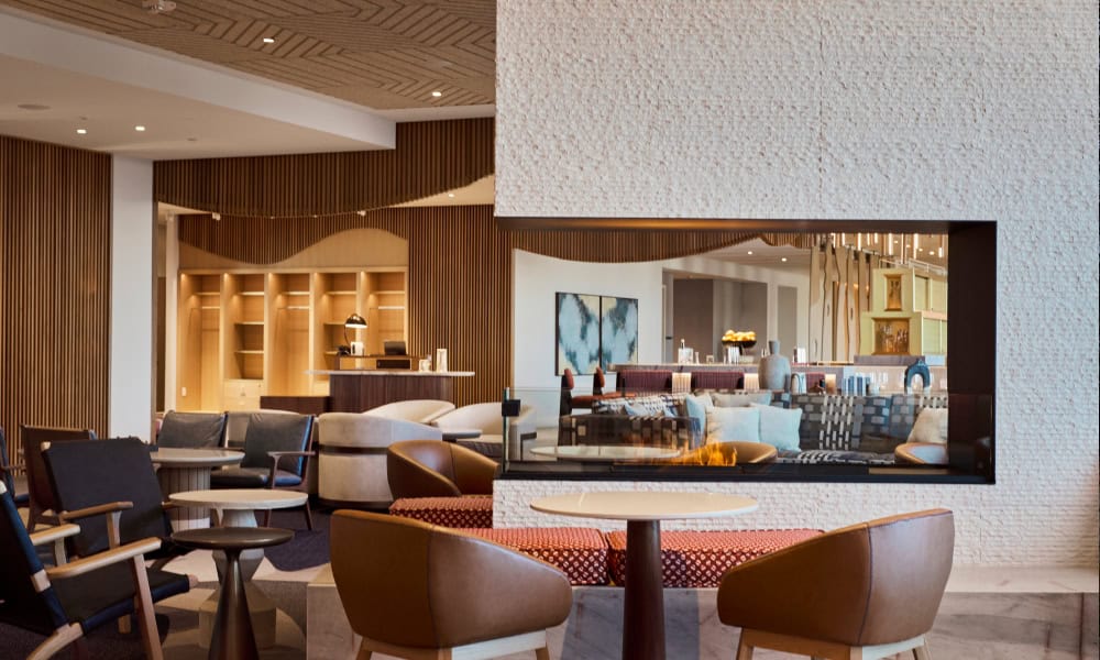 Elegant lounge with a glass-enclosed fireplace, upholstered seating, and contemporary mountain-inspired decor.